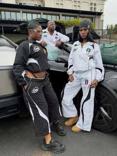 Two women wearing custom manufactured streetwear tracksuits standing by a car