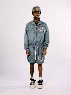 Male model wearing a custom manufactured blue streetwear jacket and shorts set with patch branding