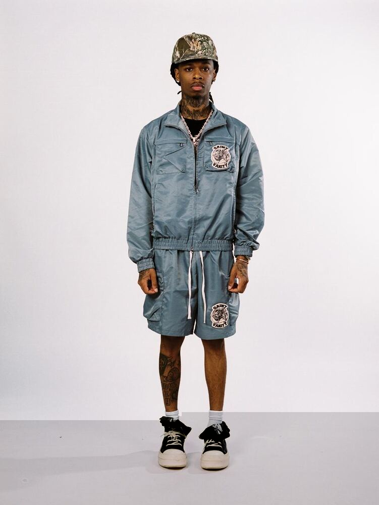 Clean studio photo of a custom manufactured blue streetwear jacket and shorts set with patch branding