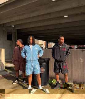 Three young men wearing custom streetwear windbreaker tracksuits under a bridge